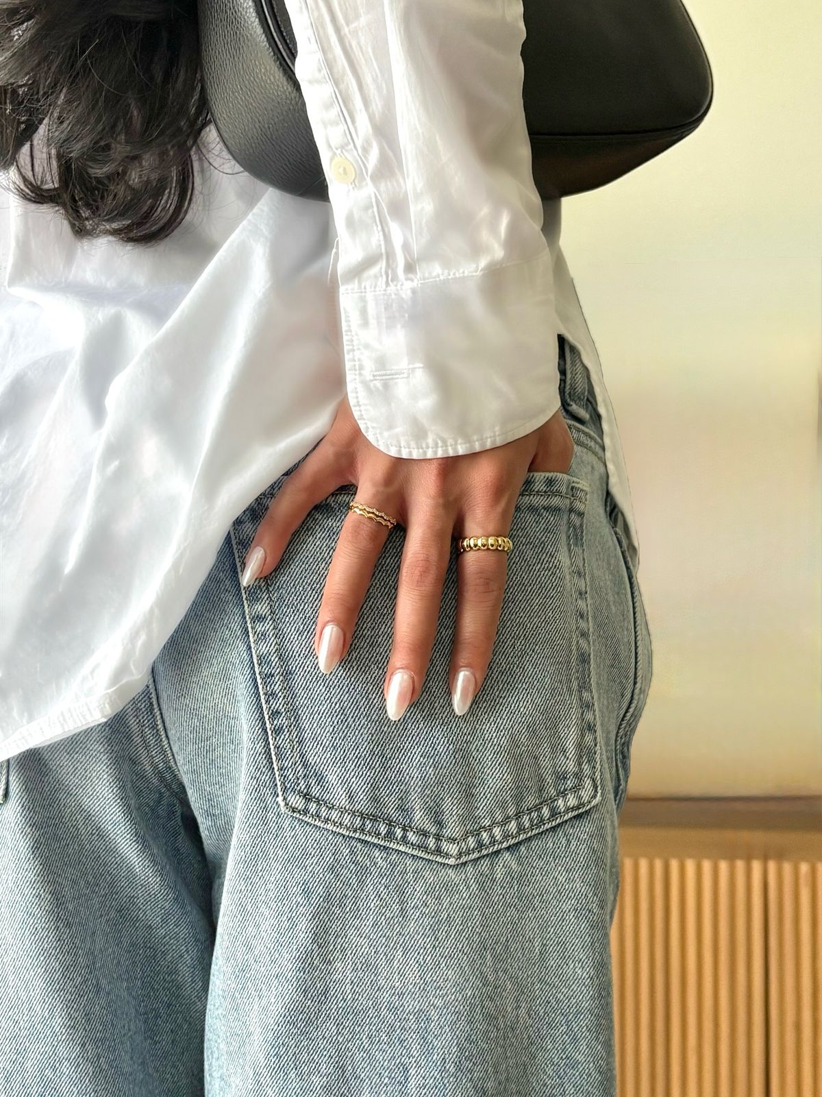Your hand with soft neutral nails resting in the back pocket of blue jeans